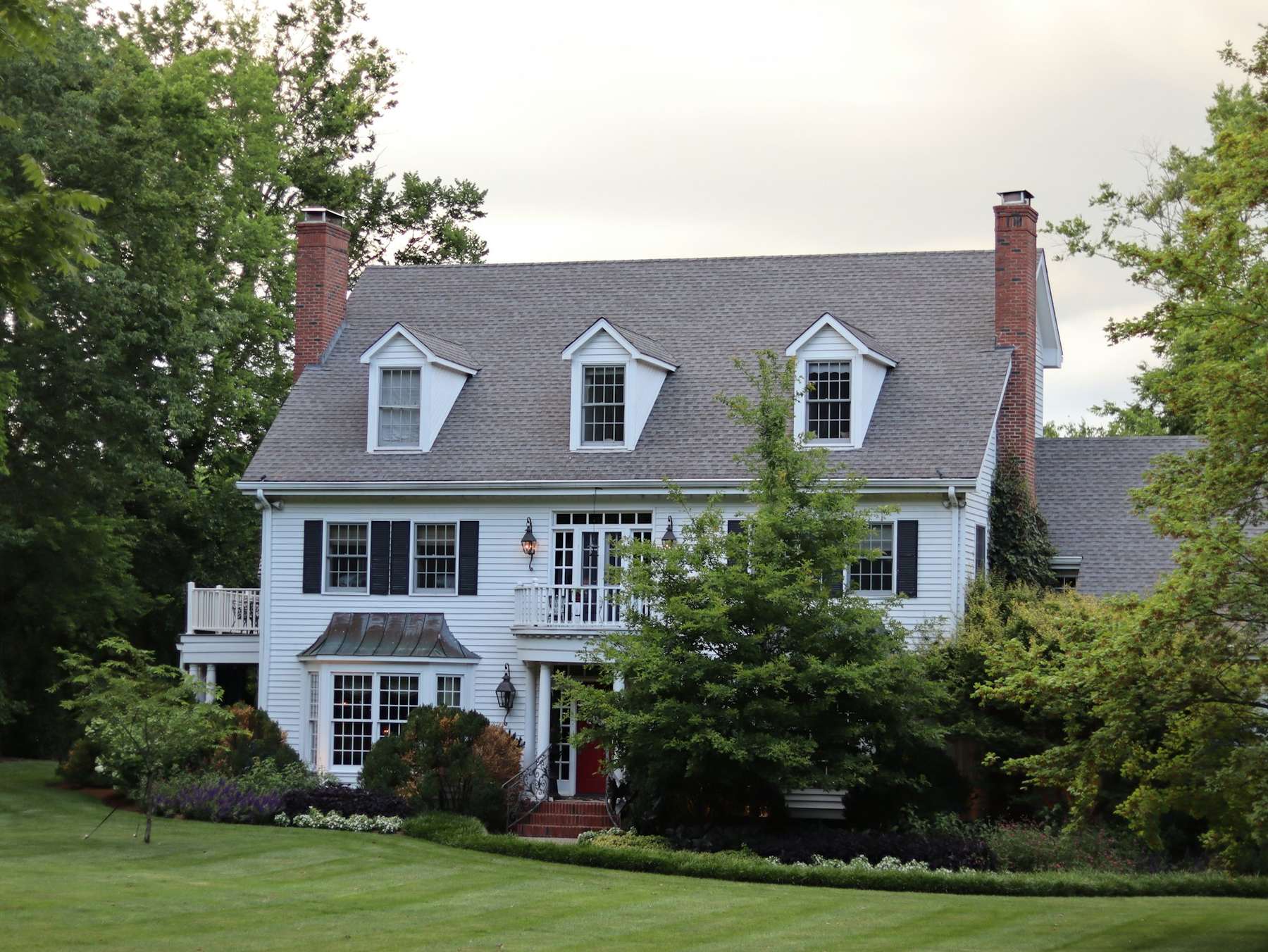 Tudor-revival family home with a steep shingled roof on a sunny green lawn
