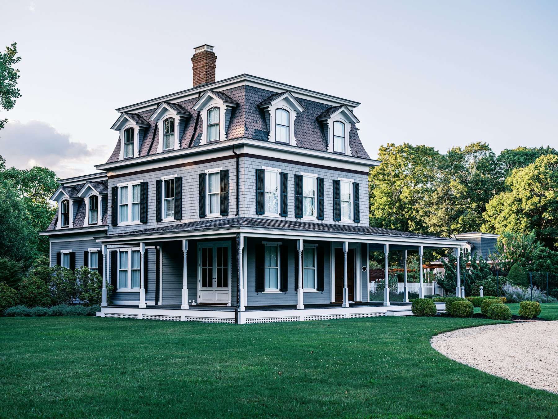 Grey Second Empire house with a mansard roof and wraparound porch