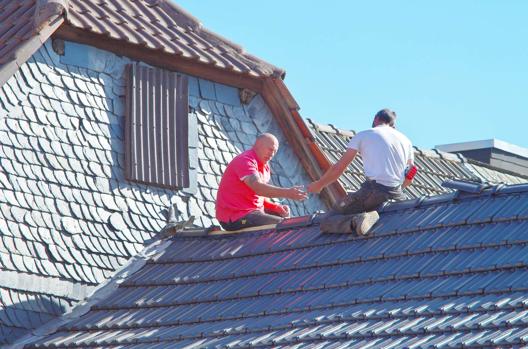 Two roofers working together on a residential roof