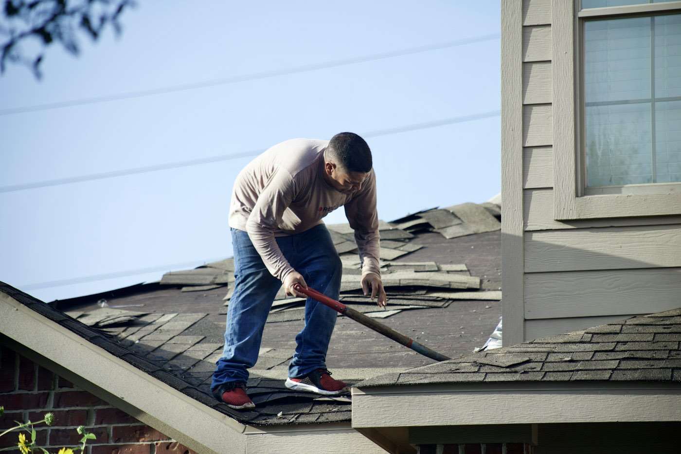 Roofer stripping old shingles from a roof